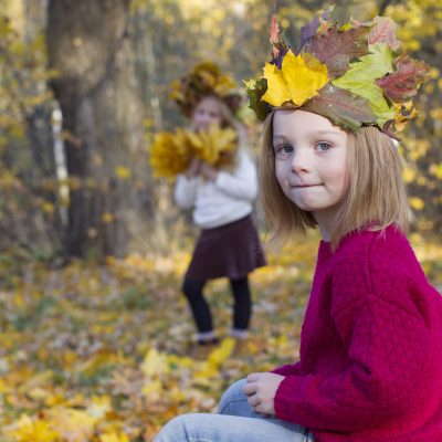 Girl in autumn park with a wreath of maple leaves